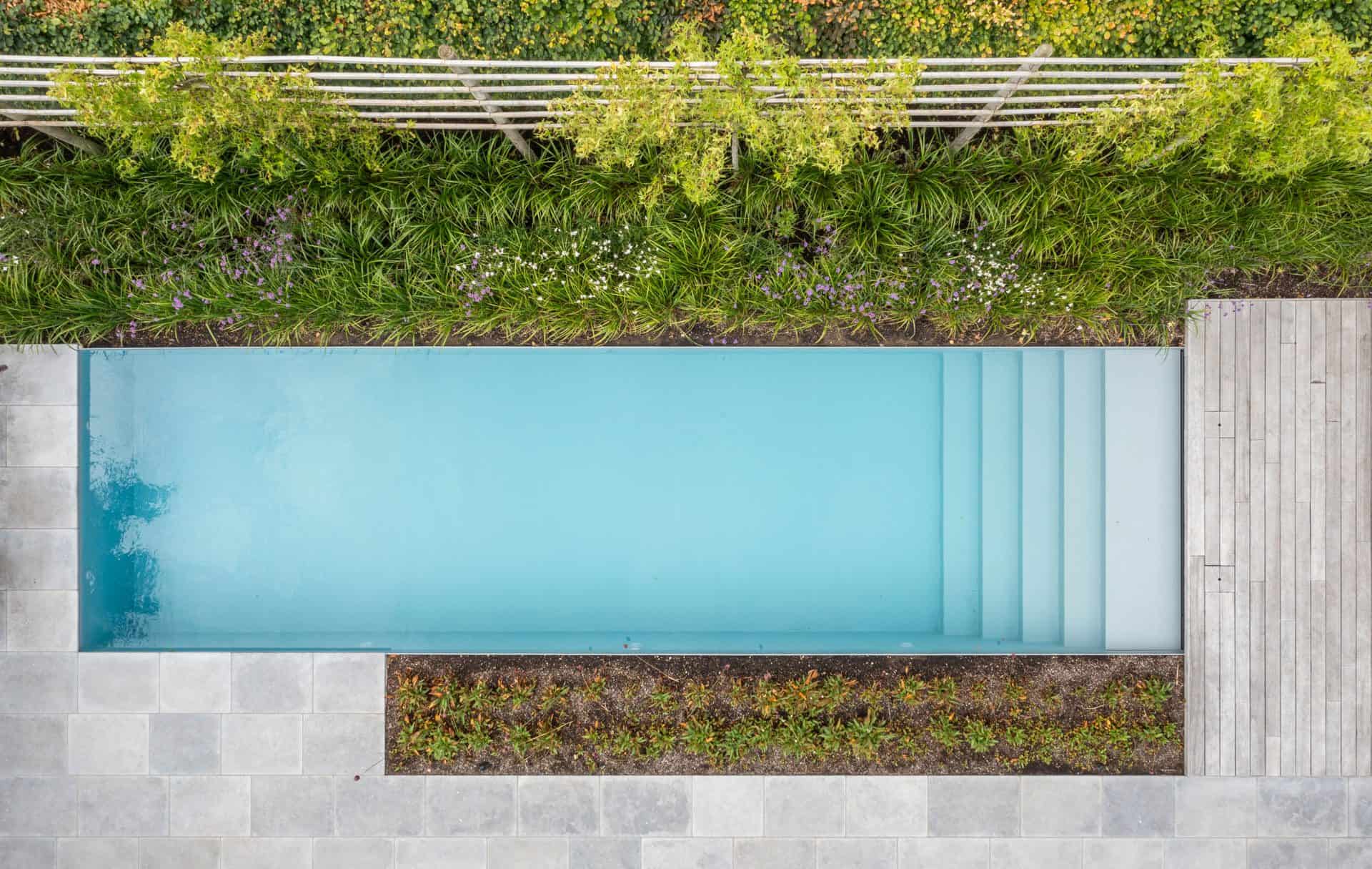 Rustige zwembad met blauwe liner en omringend groen en terras – Zwembaden Nijst.