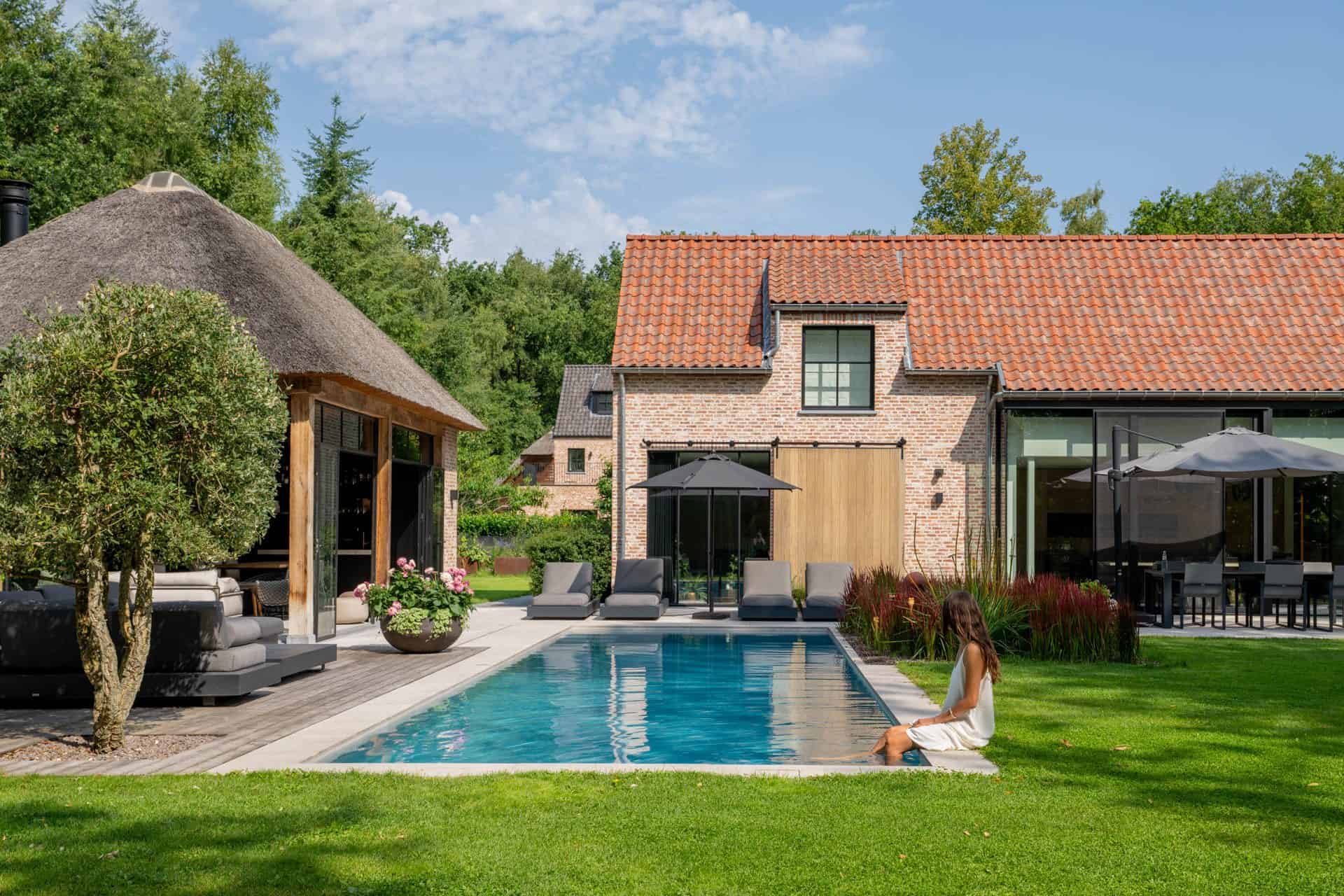 Zwembad in achtertuin met modern terras en luxe lounges, omgeven door groene tuin en natuurlijke mock-ups.